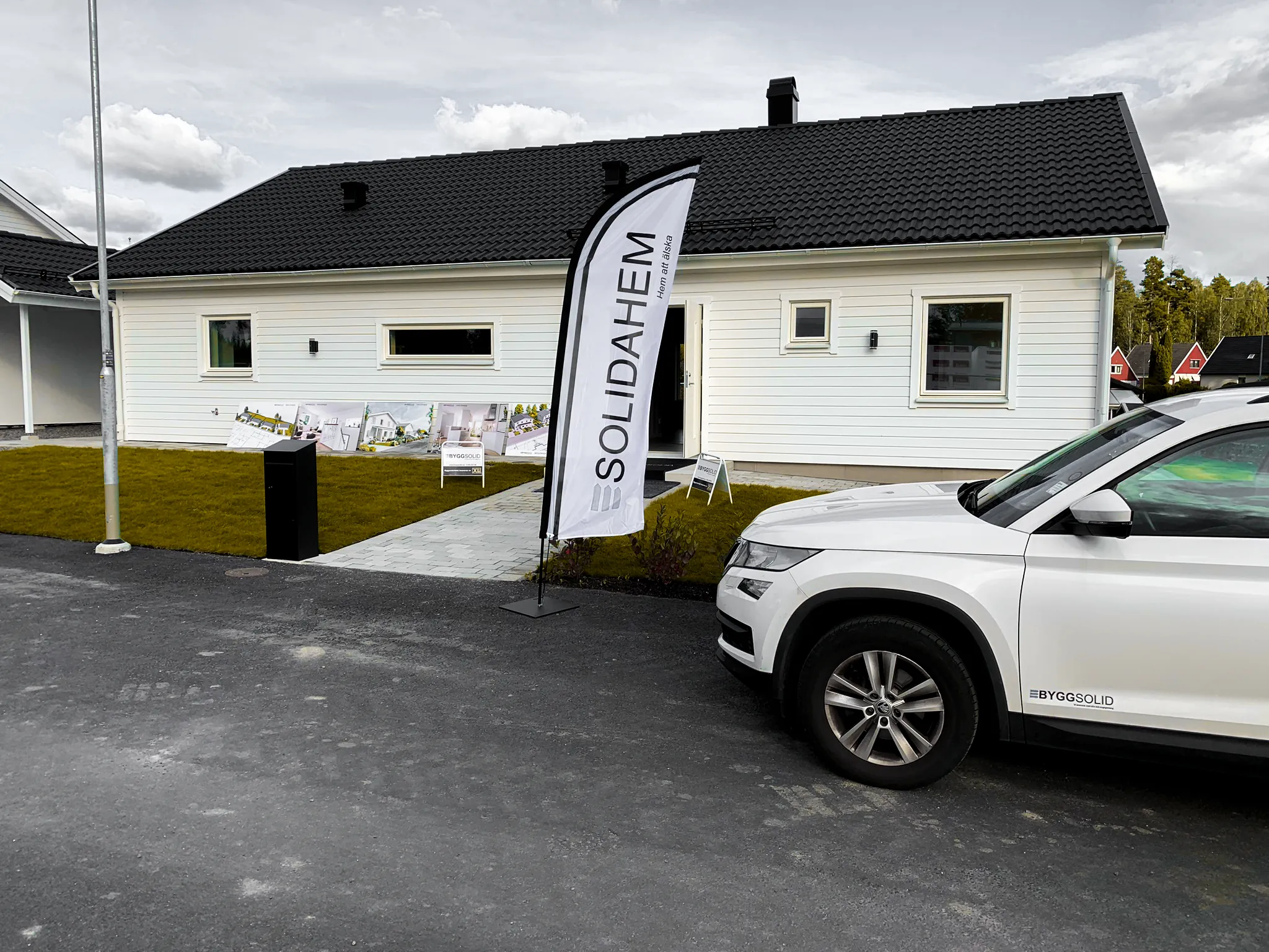 Nybyggd vit villa med svart tak, beachflagga vid infarten