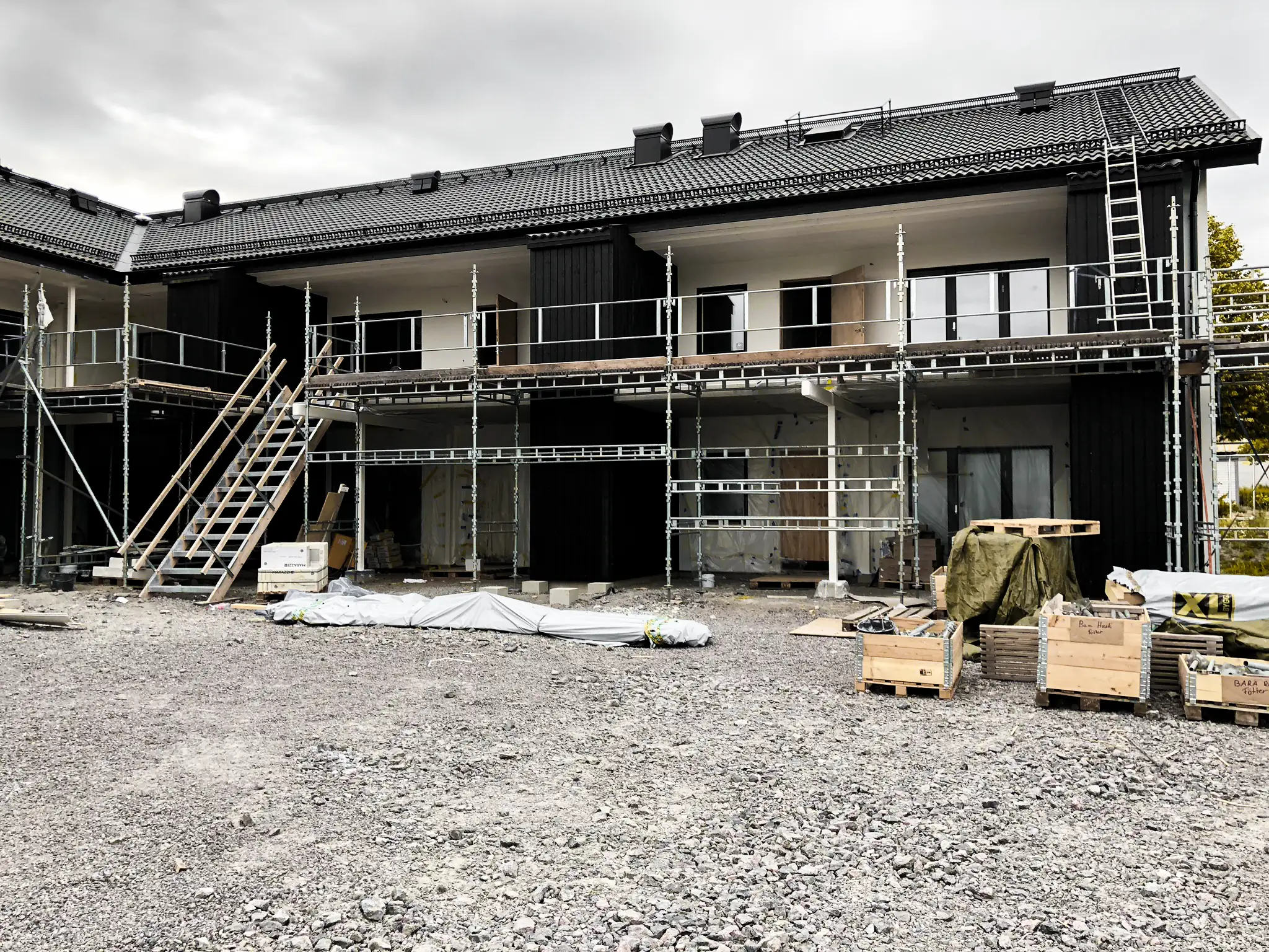Ställning längs ett nybyggt flerbostadshus med svart fasad