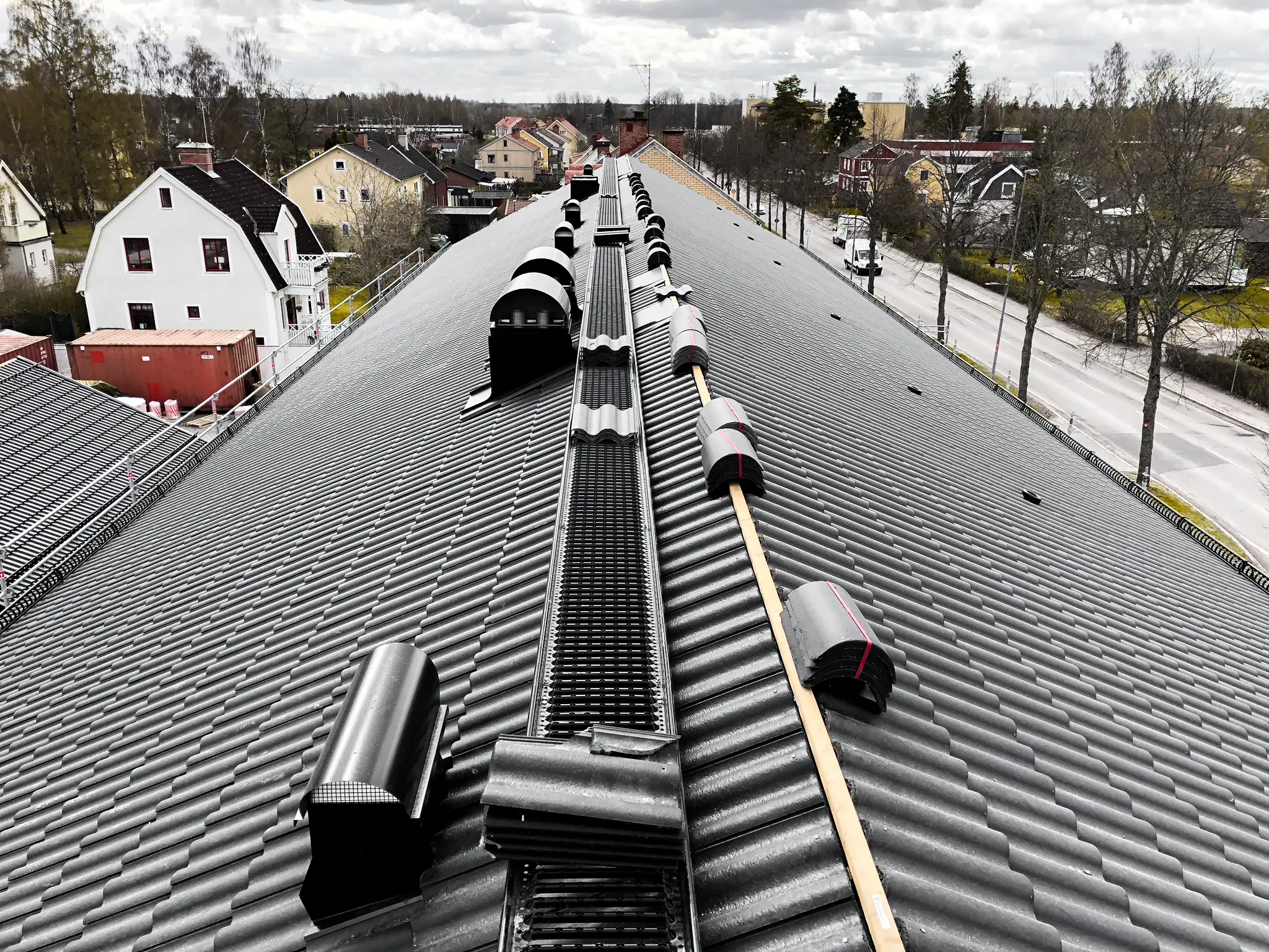 Svarta betongpannor längs nocken på ett flerbostadshus