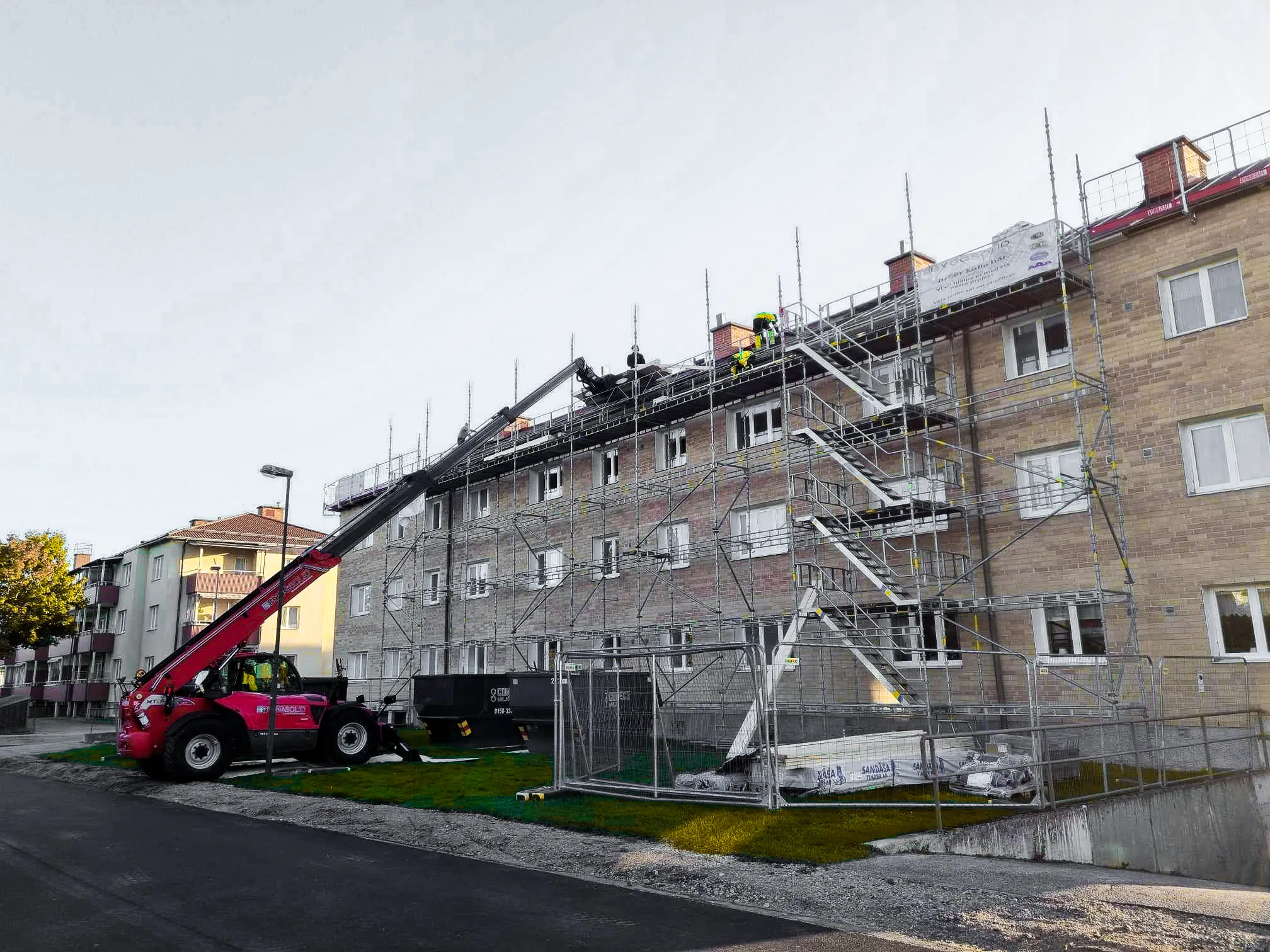 Teleskoplastaren lyfter material till ställningen runt ett flerbostadshus